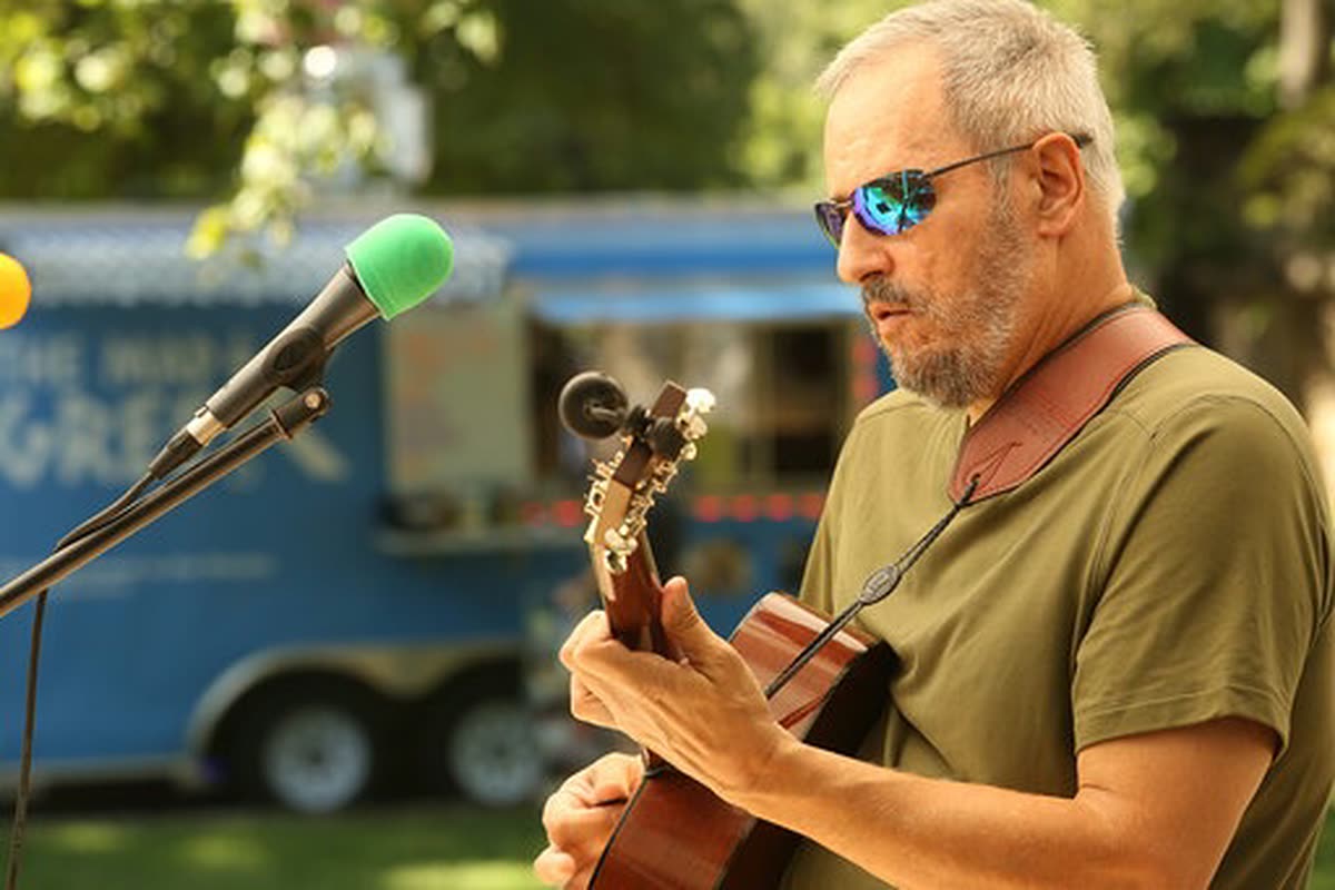 Joe Caporaso playing acoustic guitar at an outdoor set